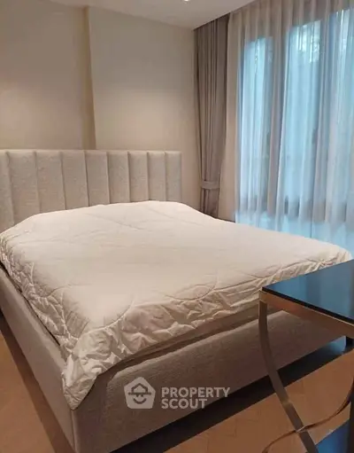 Elegant bedroom with plush bed and large window offering natural light