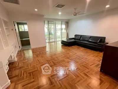 Spacious living room with elegant parquet flooring and modern black leather sofa