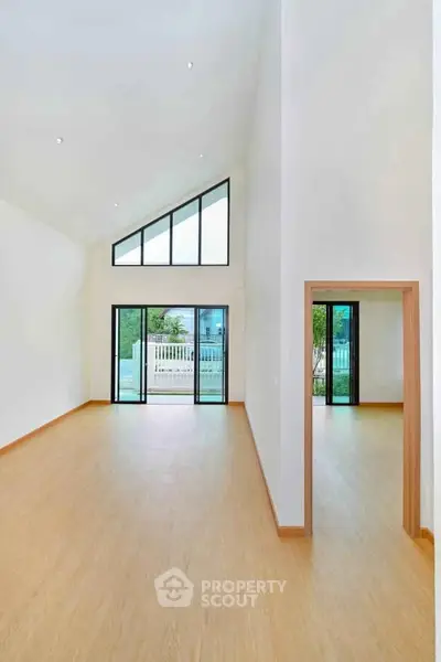 Spacious modern living room with high ceilings and large windows offering natural light and outdoor views.
