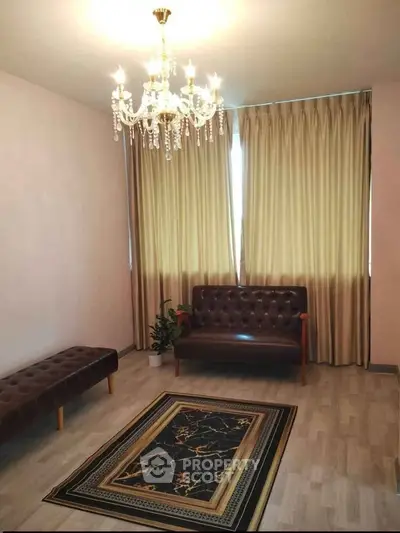 Elegant living room with chandelier, leather seating, and stylish rug, perfect for modern comfort and sophistication.