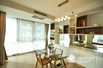 Modern dining area with glass table and built-in shelving in bright apartment