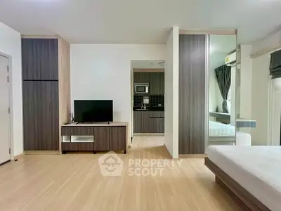 Modern studio apartment with open layout, featuring sleek wooden flooring and contemporary furnishings.