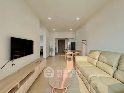 Spacious living room with modern furnishings, sleek TV unit, and an open layout leading to a well-equipped kitchen, perfect for entertaining.