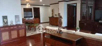 Spacious living room with elegant wooden furniture and open dining area, perfect for entertaining guests.