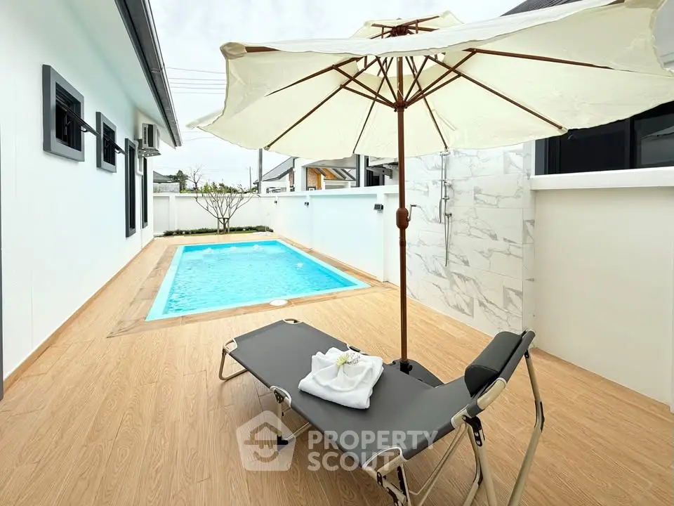 Luxurious private pool area with sun lounger and umbrella, perfect for relaxation and leisure.