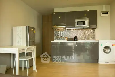 Modern kitchen with sleek cabinets, fridge, and washing machine in a cozy apartment.