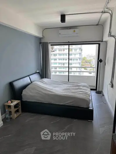 Modern bedroom with large window and city view, featuring sleek design and ample natural light.
