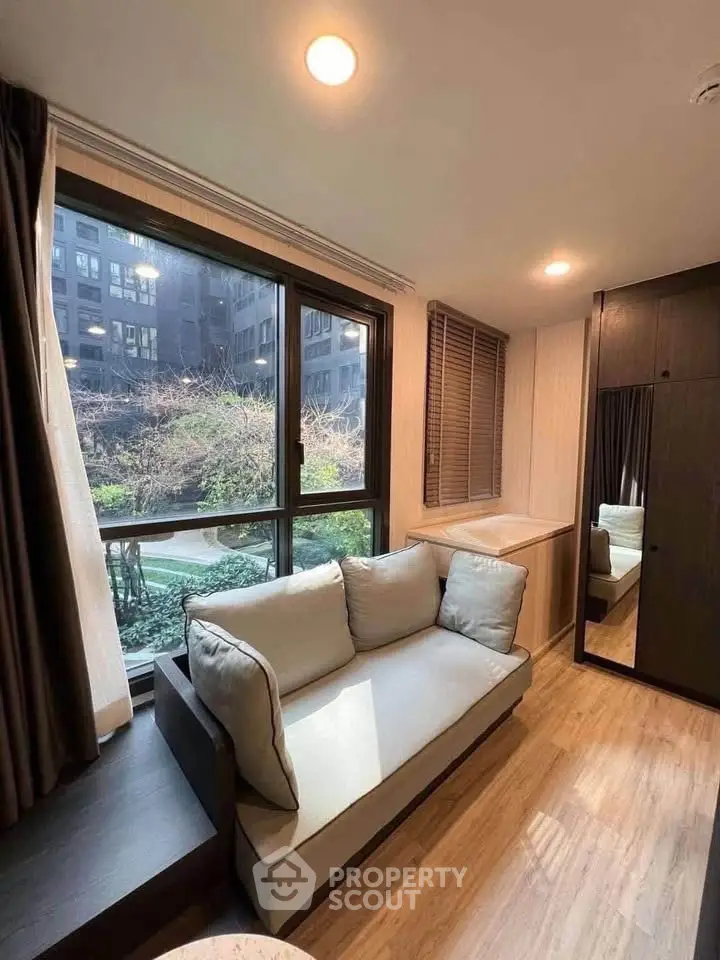 Cozy living room with large window and garden view in modern apartment
