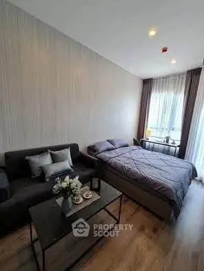 Modern studio apartment with cozy bed and stylish sofa in a well-lit room.
