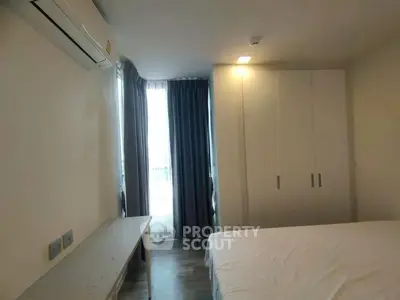 Cozy bedroom with natural light, featuring a large window, air conditioning, and ample closet space.