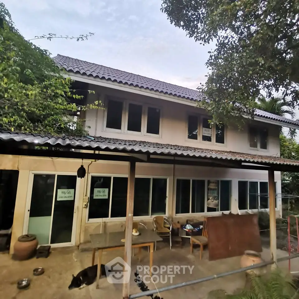 Charming two-story house with spacious outdoor area and lush greenery, perfect for serene living.
