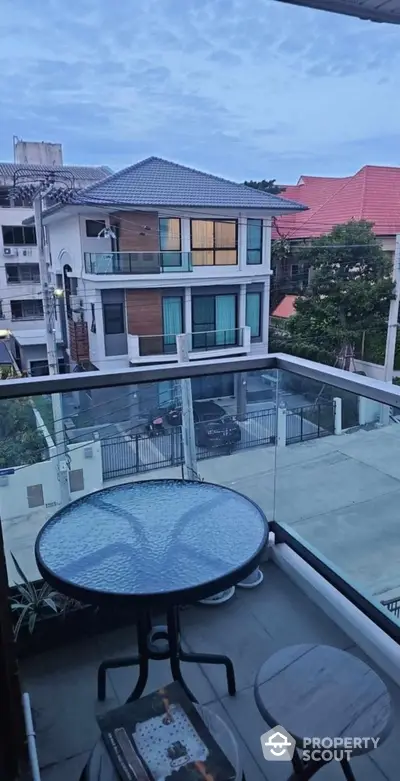 Charming balcony view with modern glass railing overlooking residential neighborhood