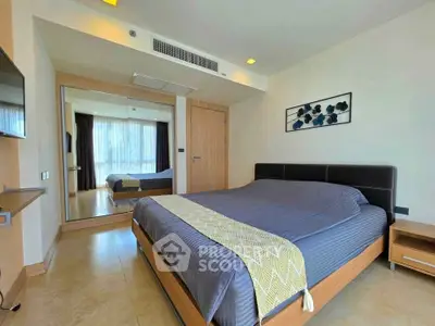 Spacious modern bedroom with large mirror and stylish decor in a luxury apartment.