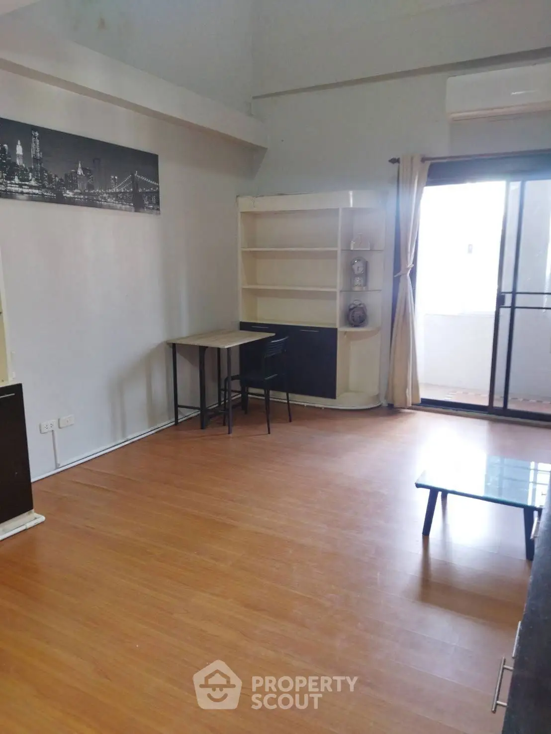 Spacious living room with wooden flooring and balcony access in modern apartment.