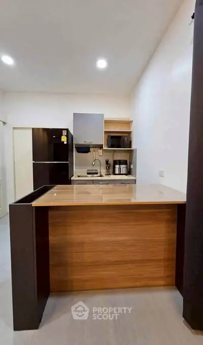 Modern kitchen with sleek appliances and open layout, featuring a stylish wooden island and contemporary lighting.