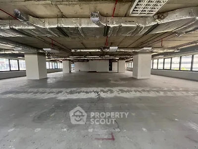 Spacious open-plan commercial space with large windows and exposed ceiling.
