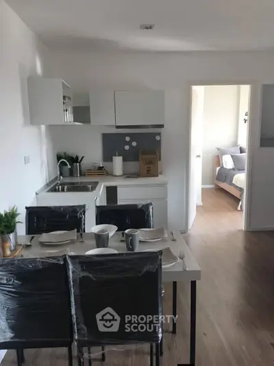 Modern open-layout kitchen with dining area and view into cozy bedroom.