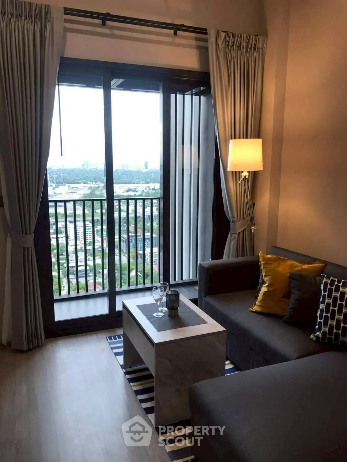 Modern living room with balcony view, cozy seating, and stylish decor in urban apartment.
