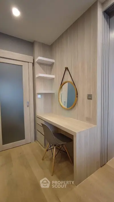 Modern study nook with wooden desk, chair, and round mirror in stylish apartment.