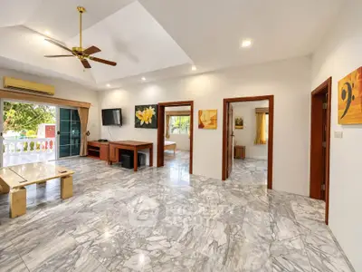 Spacious living room with marble flooring and modern decor, featuring a ceiling fan and large windows for natural light.
