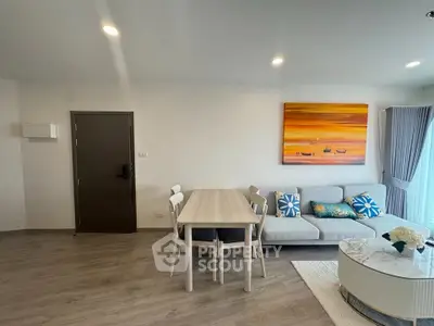 Modern living room with stylish decor and natural light, featuring a cozy sofa and dining area.