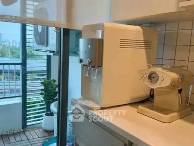 Modern kitchen corner with coffee machine and water dispenser, overlooking a balcony with city view.