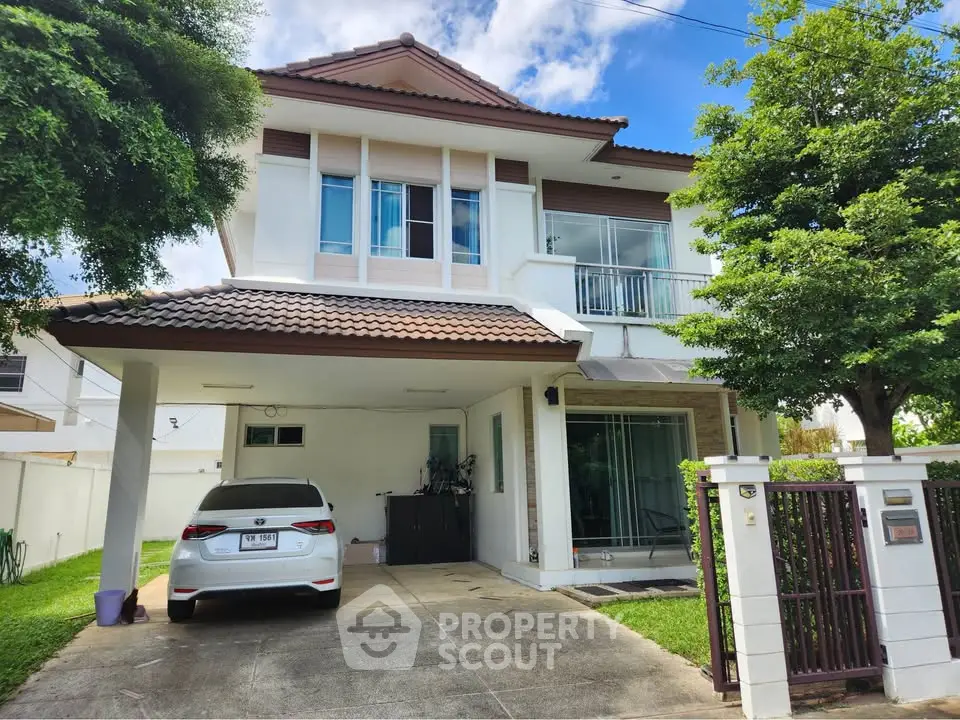 Charming two-story house with carport and lush greenery, perfect for family living.