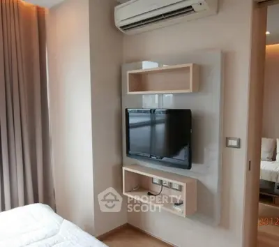 Modern bedroom with wall-mounted TV and air conditioning unit, featuring sleek design and cozy ambiance.