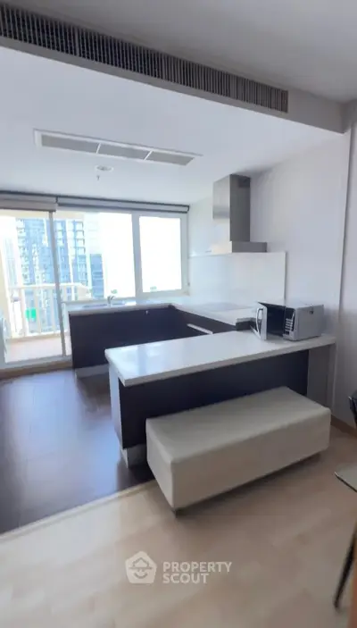 Modern kitchen with open layout and city view, featuring sleek appliances and a breakfast bar.