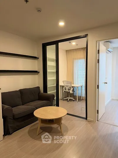 Modern living room with study area, featuring sleek furniture and ample natural light.