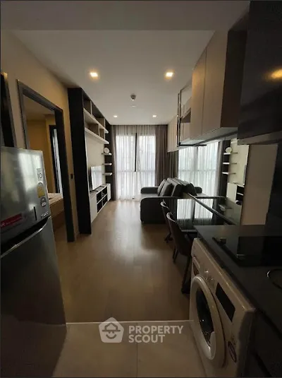 Modern apartment interior with open kitchen and living area, featuring sleek appliances and stylish decor.