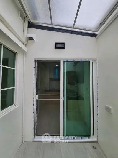 Modern enclosed balcony with sliding glass doors and natural light