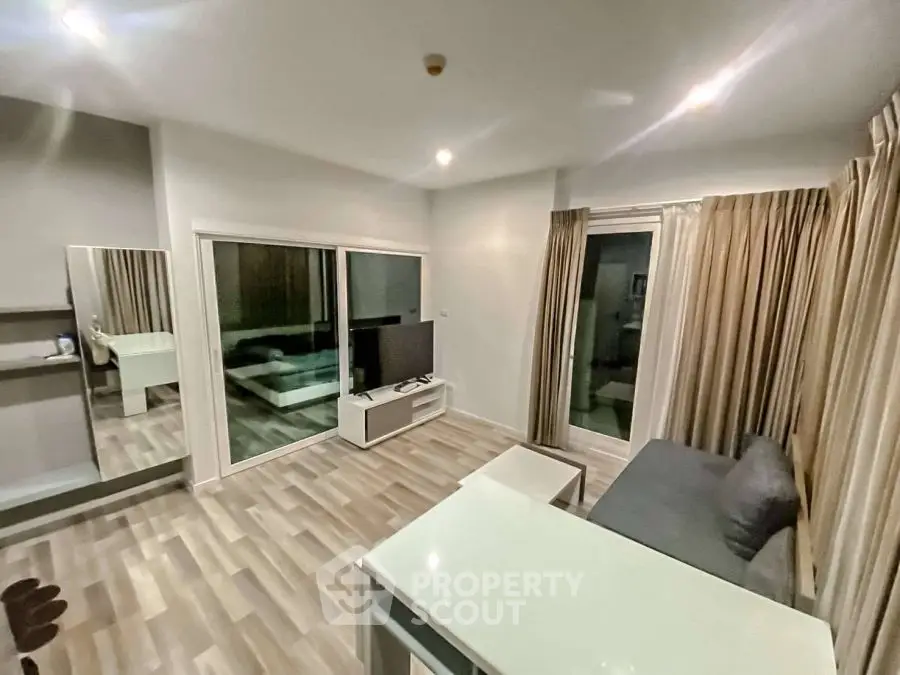 Modern living room with sleek design, featuring a TV, sofa, and large windows for natural light.