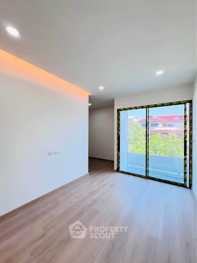 Modern unfurnished room with large window and wooden flooring, ideal for customization.