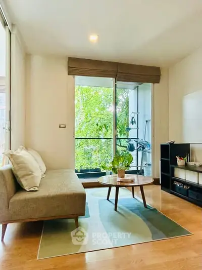 Charming living room with modern decor and large window overlooking greenery.