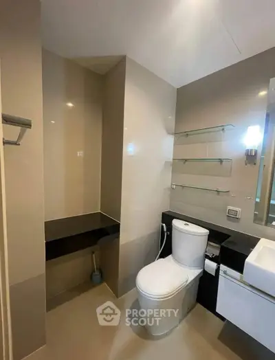 Modern bathroom with sleek fixtures and neutral tones, featuring a toilet and stylish sink area.