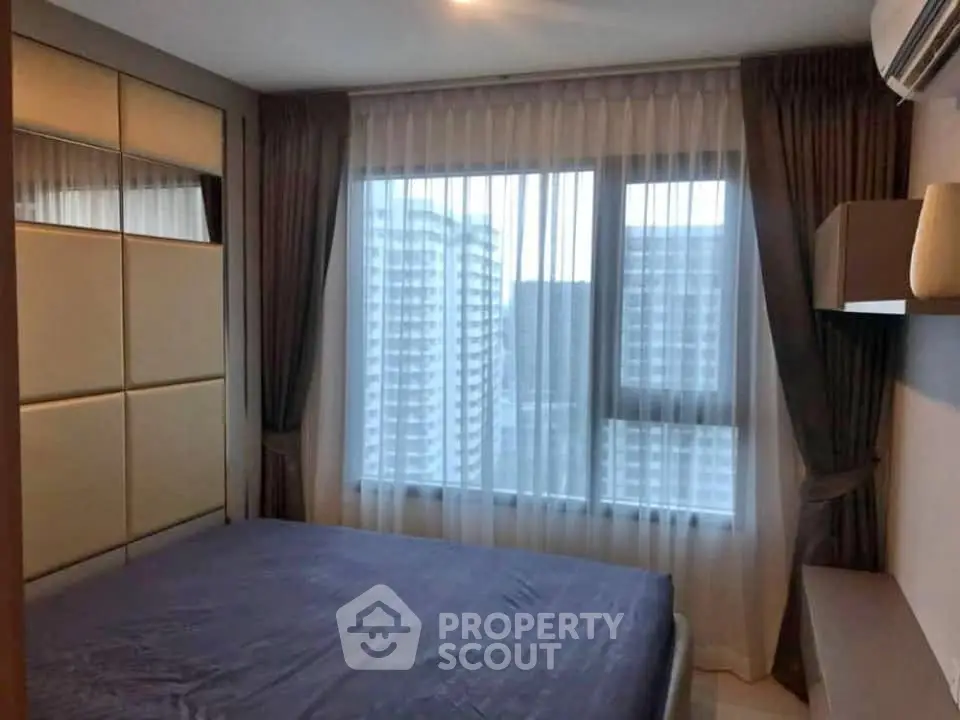 Modern bedroom with large window and city view in high-rise apartment