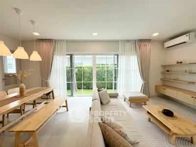 Spacious modern living room with natural light, wooden furniture, and garden view, perfect for family gatherings.