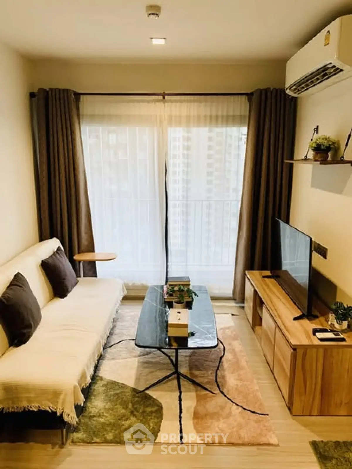 Cozy living room with modern decor, large window, and stylish furniture in a high-rise apartment.