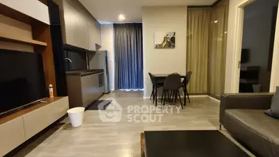 Modern living room with open kitchen and dining area, featuring sleek furniture and contemporary design.