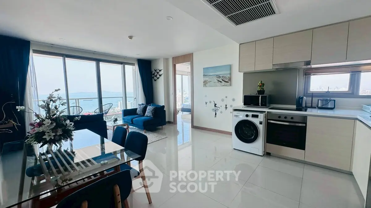 Modern open-plan living room with ocean view, sleek kitchen, and elegant dining area.