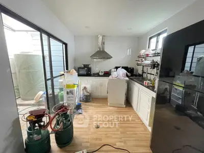 Spacious kitchen with modern appliances and open layout, featuring a sleek black fridge and ample natural light.
