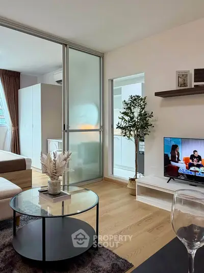 Modern living room with glass partition, cozy decor, and natural light in a stylish apartment.