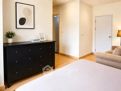 Modern bedroom with stylish black dresser and cozy beige sofa