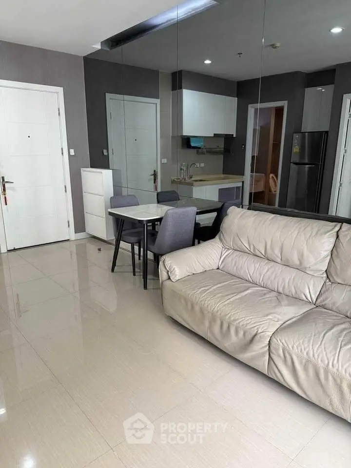 Modern living room with sleek furniture and mirrored wall in contemporary apartment.