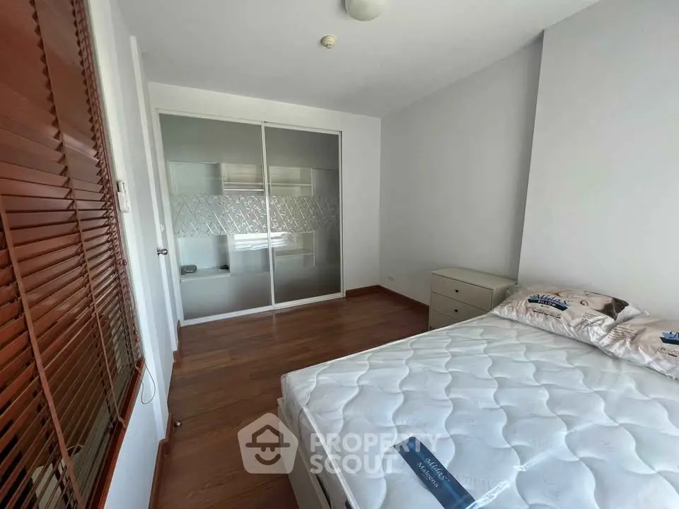 Spacious bedroom with wooden flooring and built-in closet in modern apartment.