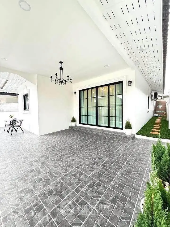 Spacious modern patio with elegant chandelier and garden path, perfect for outdoor relaxation.