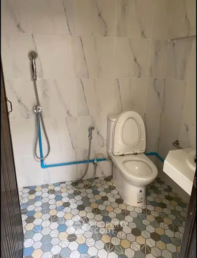 Modern bathroom with geometric tile flooring and sleek fixtures.