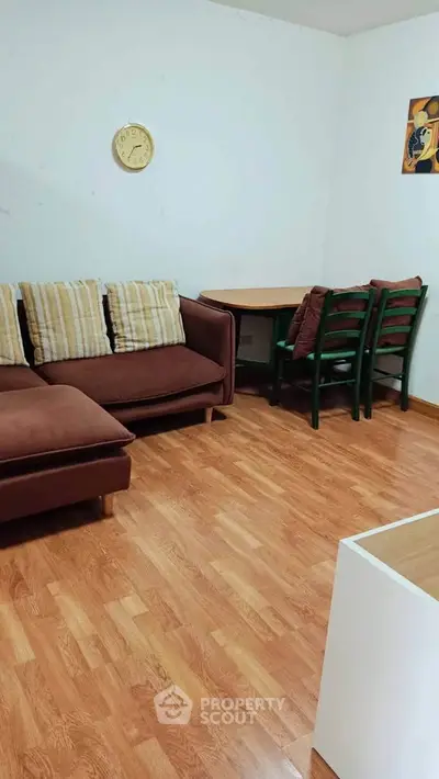 Cozy living room with brown sofa and wooden floor, perfect for relaxation.