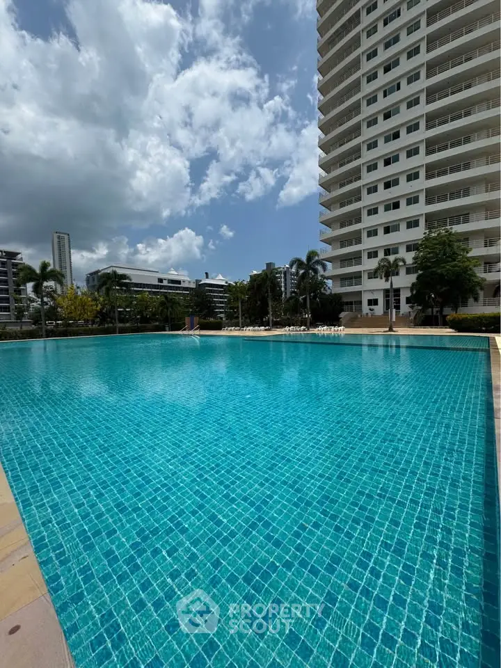 Luxurious high-rise building with a stunning outdoor pool and clear blue skies, perfect for relaxation.